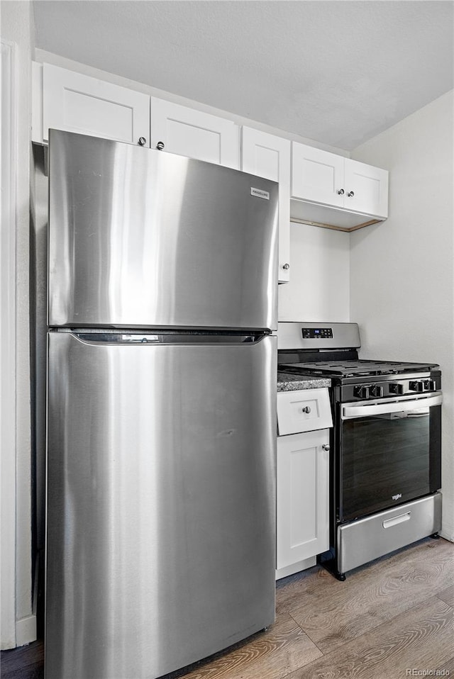 kitchen featuring appliances with stainless steel finishes, white cabinetry, and light wood-style floors