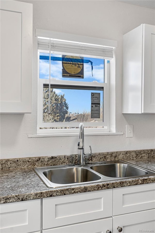 kitchen with a sink, a wealth of natural light, and white cabinets