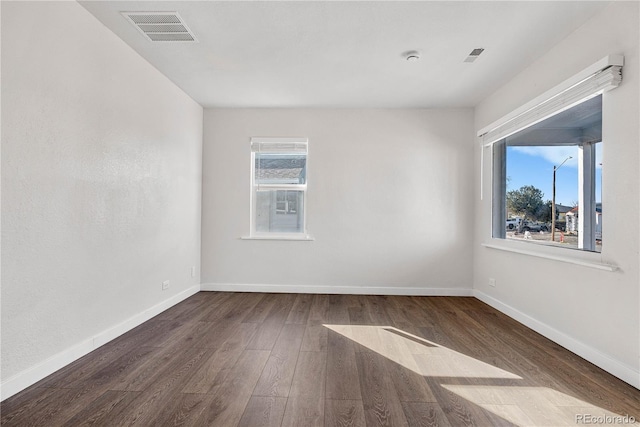 spare room featuring visible vents, baseboards, and wood finished floors