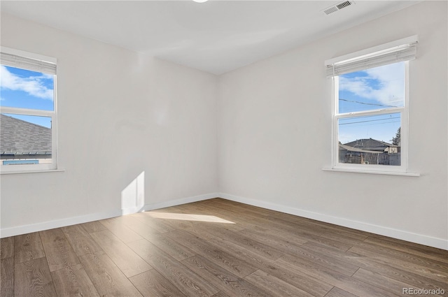 unfurnished room featuring visible vents, baseboards, and wood finished floors