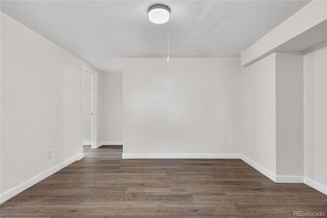 spare room featuring dark wood-style floors, a textured ceiling, and baseboards