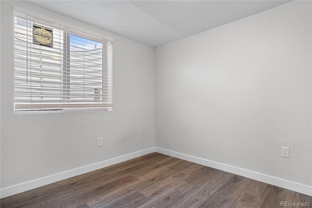 unfurnished room featuring baseboards and dark wood finished floors