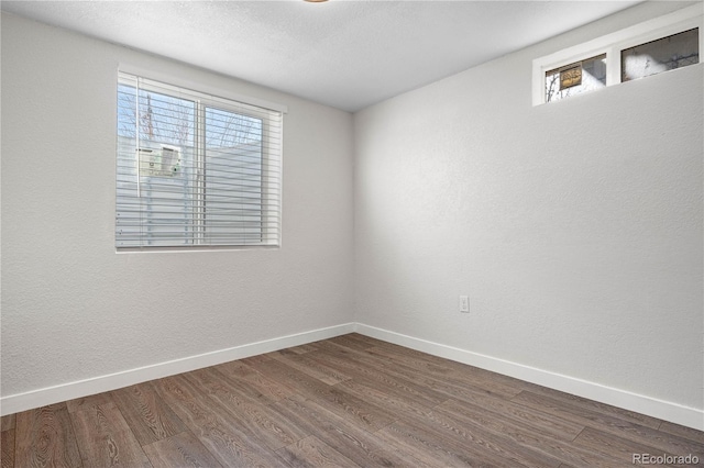 unfurnished room with baseboards and dark wood finished floors