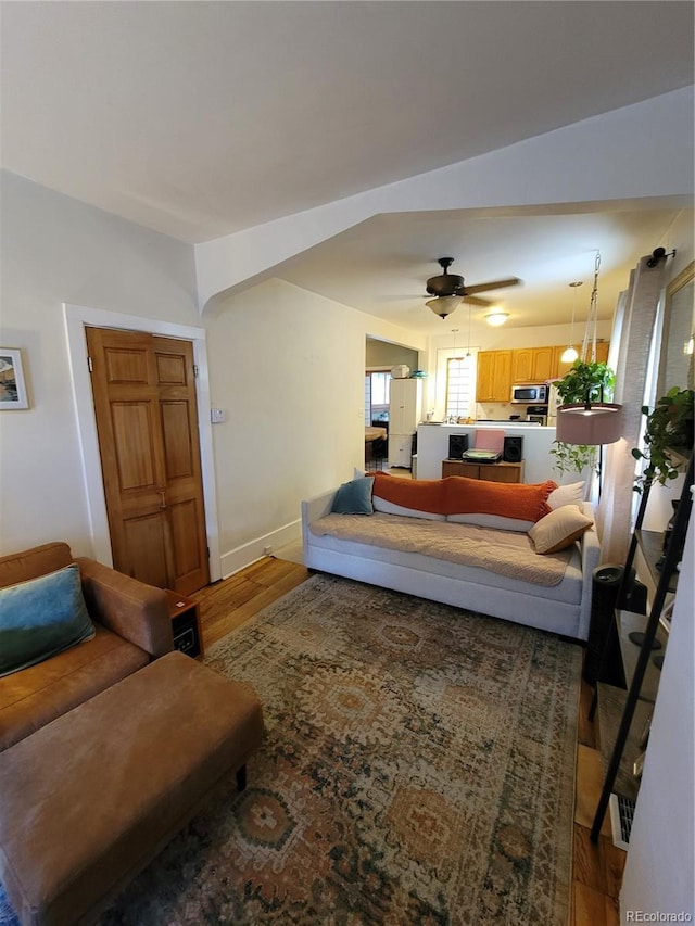 living room featuring ceiling fan, baseboards, and wood finished floors