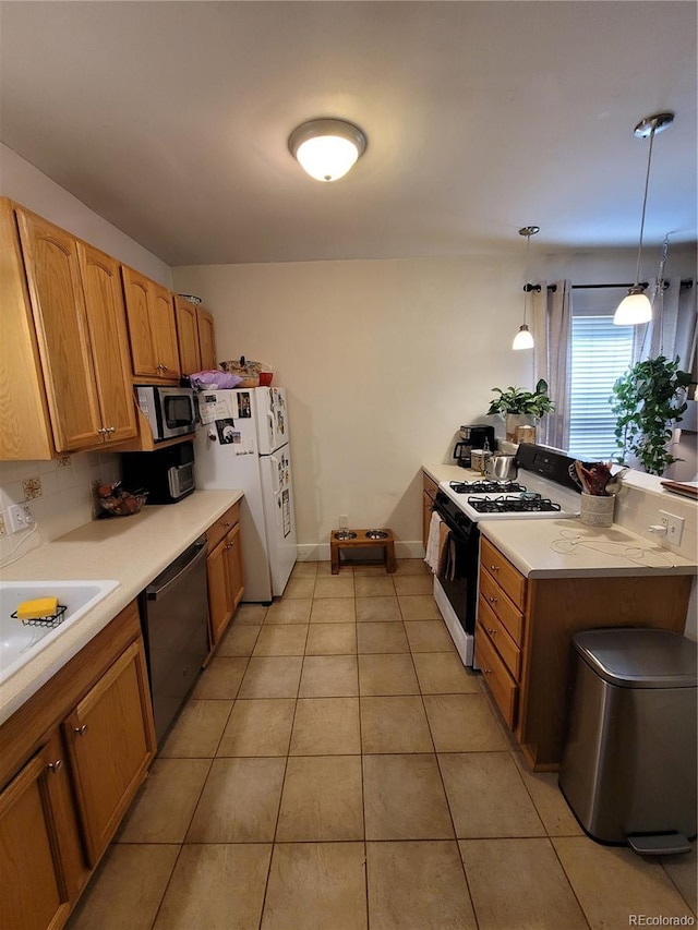 kitchen with a peninsula, appliances with stainless steel finishes, light tile patterned floors, and light countertops