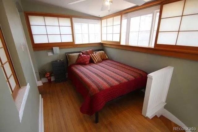 bedroom with ceiling fan, baseboards, and wood finished floors