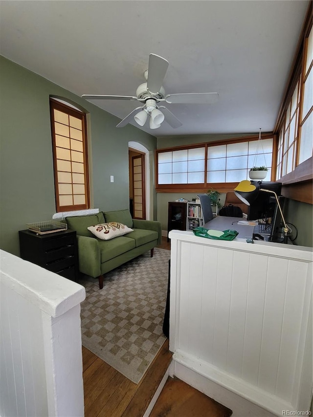 interior space featuring arched walkways, wood finished floors, and a ceiling fan