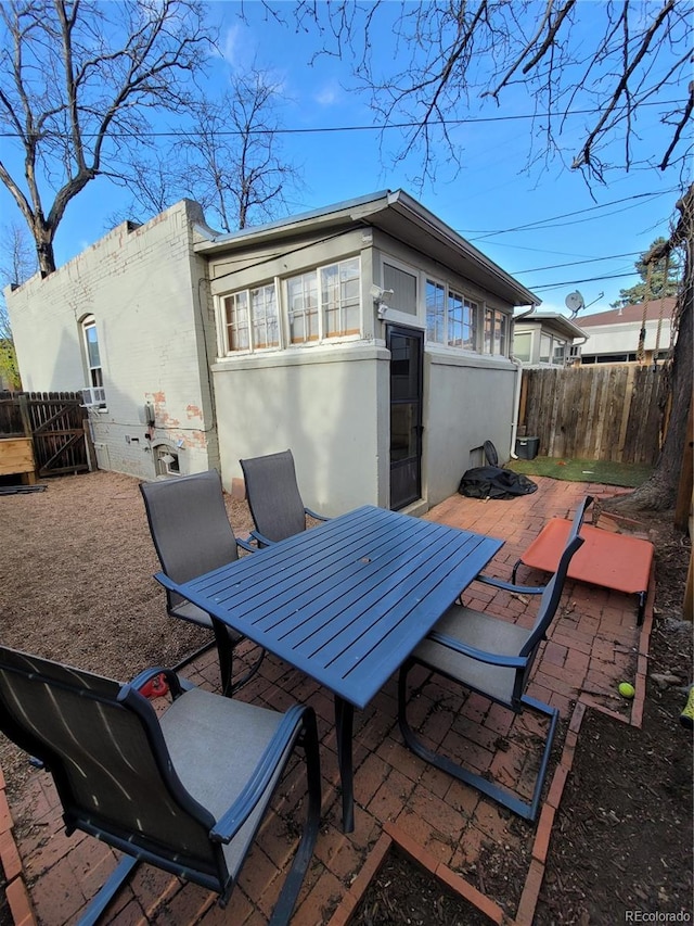 rear view of property featuring a patio, outdoor dining area, a fenced backyard, and stucco siding