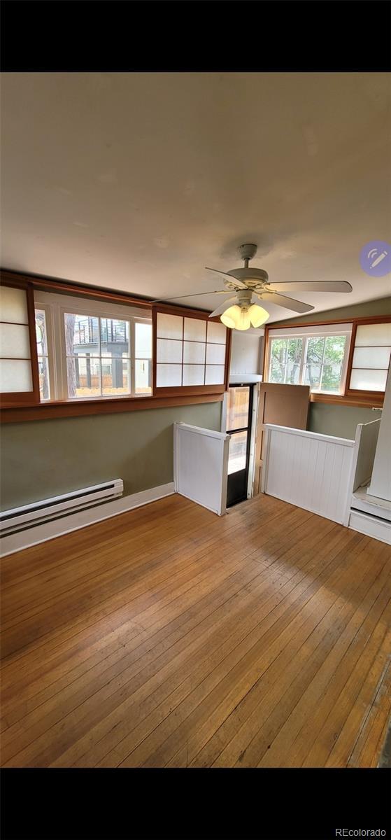 914 E Iowa Ave, Denver, CO 80210 - unfurnished living room featuring a baseboard heating unit, hardwood / wood-style flooring, and a ceiling fan