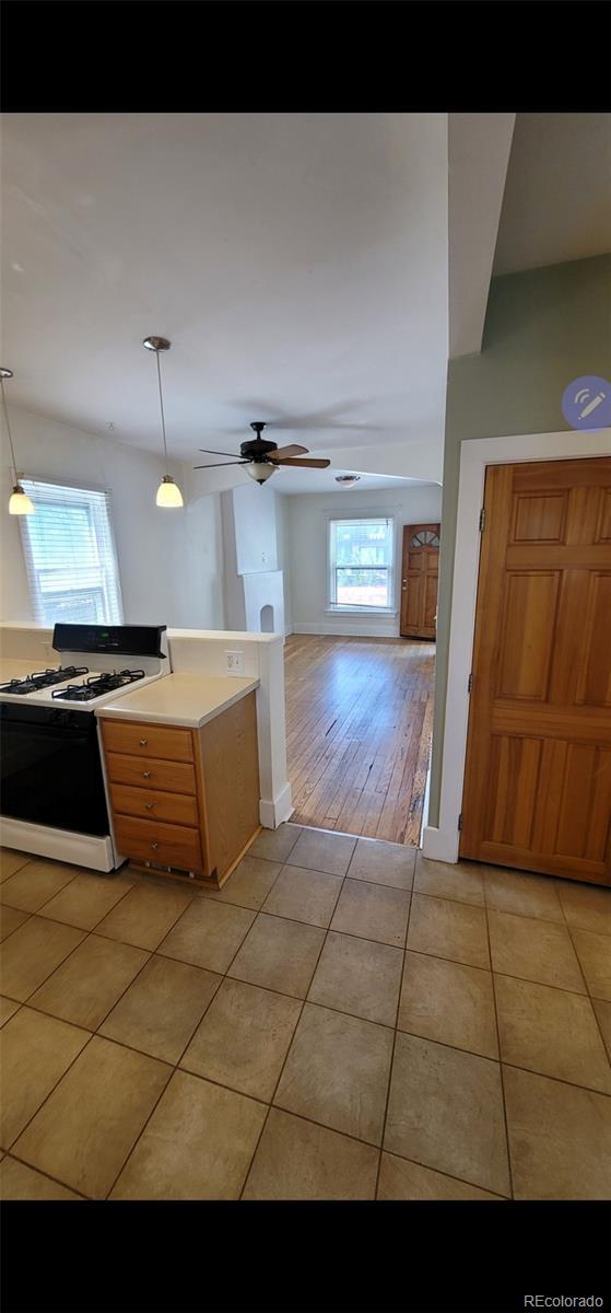 914 E Iowa Ave, Denver, CO 80210 - kitchen featuring gas range gas stove, healthy amount of natural light, light tile patterned floors, and light countertops