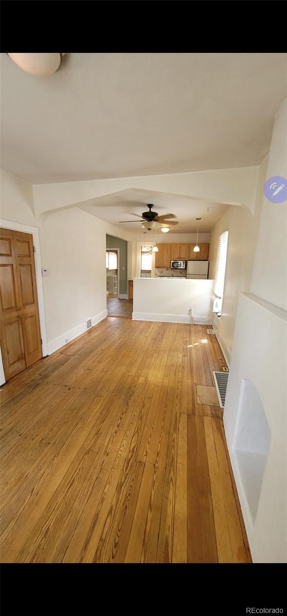 914 E Iowa Ave, Denver, CO 80210 - unfurnished living room featuring light wood finished floors, plenty of natural light, a ceiling fan, and baseboards