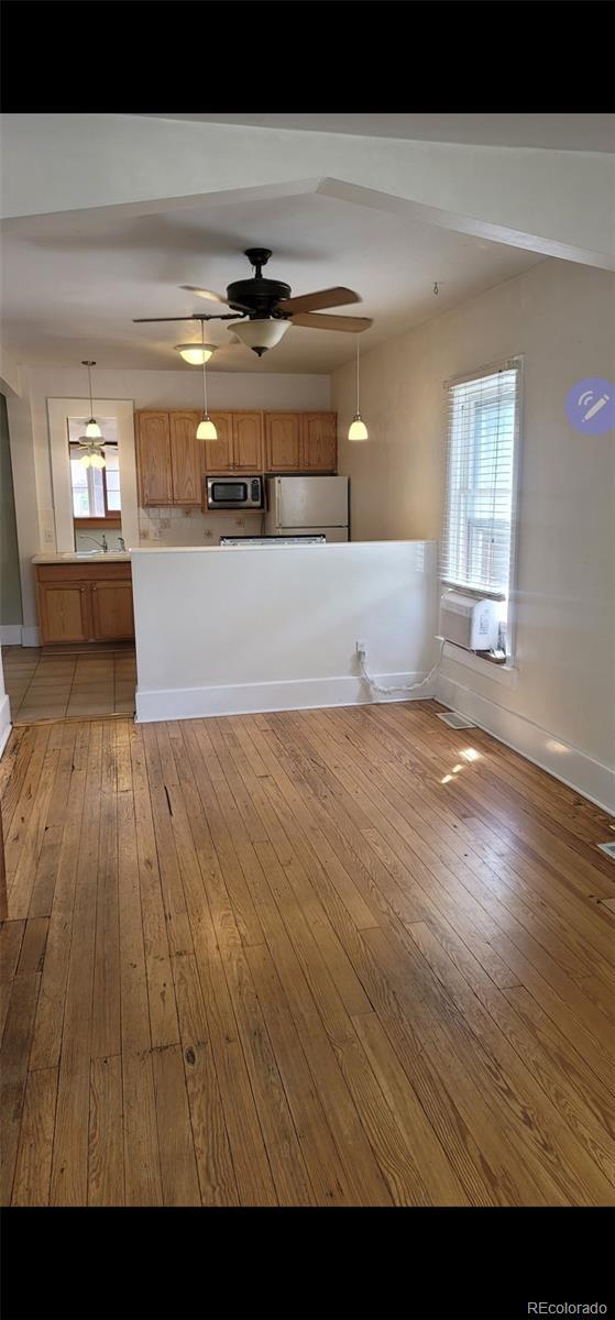 914 E Iowa Ave, Denver, CO 80210 - kitchen featuring stainless steel microwave, ceiling fan, light wood finished floors, pendant lighting, and cooling unit