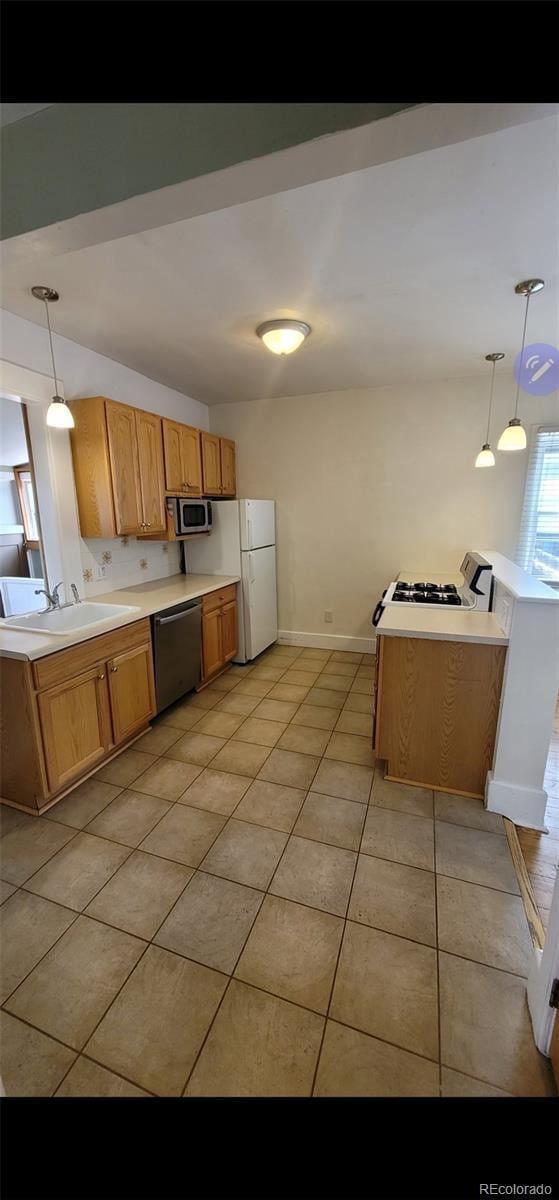 914 E Iowa Ave, Denver, CO 80210 - kitchen with stainless steel appliances, a sink, light countertops, light tile patterned flooring, and hanging light fixtures