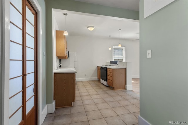 914 E Iowa Ave, Denver, CO 80210 - kitchen featuring white gas range oven, light countertops, light tile patterned floors, hanging light fixtures, and brown cabinetry
