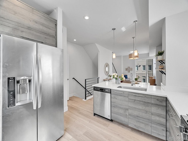 kitchen with gray cabinetry, a sink, stainless steel appliances, light wood-style floors, and light countertops