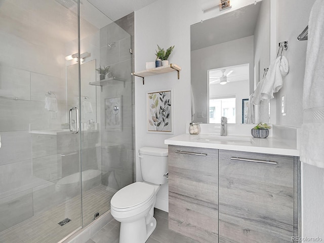 full bath with tile patterned floors, toilet, a ceiling fan, a shower stall, and vanity