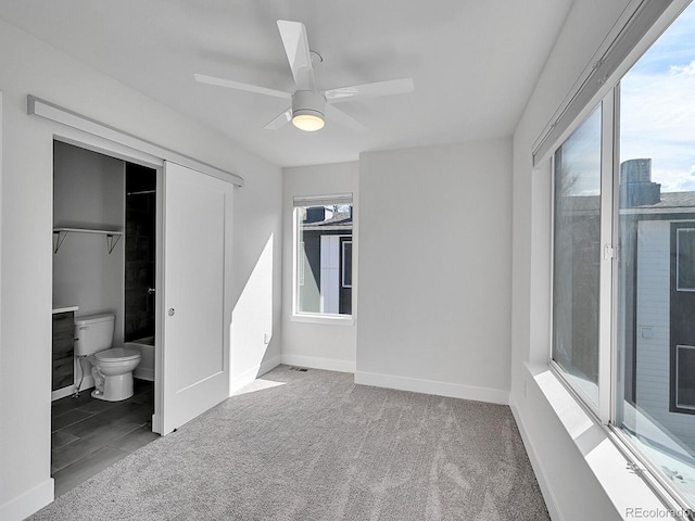 unfurnished bedroom featuring baseboards, multiple windows, and carpet