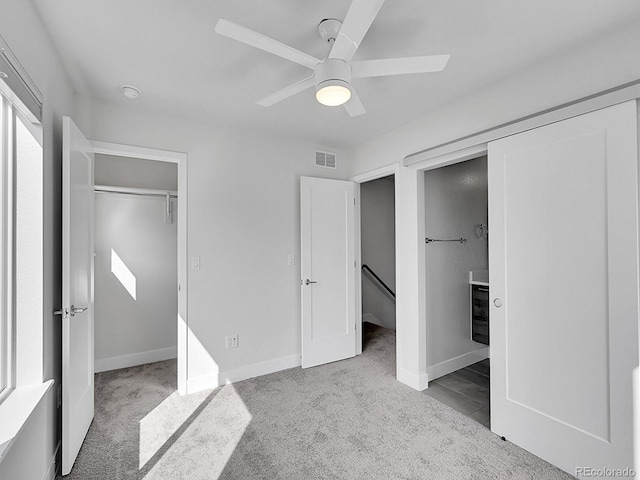 unfurnished bedroom featuring visible vents, carpet flooring, a walk in closet, and baseboards