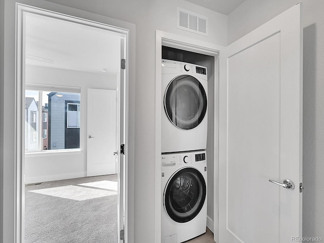 washroom with laundry area, stacked washer / dryer, carpet flooring, and visible vents