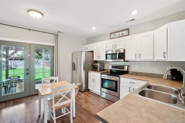 6142 Gorham St, Frederick, CO 80530 - kitchen with appliances with stainless steel finishes, a sink, french doors, white cabinets, and wood finished floors