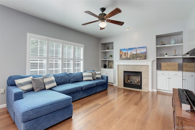 9954 Heywood St, Highlands Ranch, CO 80130 - living room with built in features, ceiling fan, light wood-type flooring, and a tile fireplace