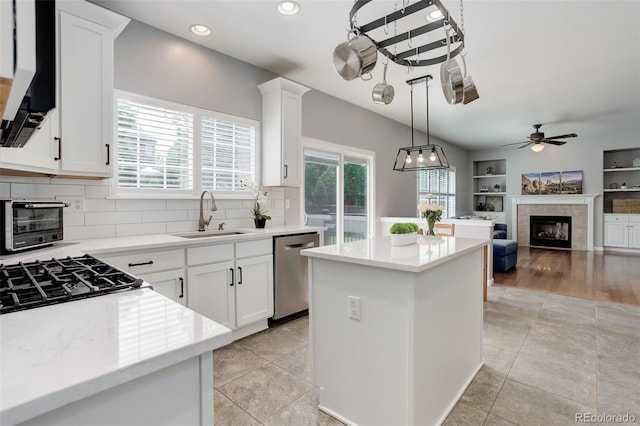 9954 Heywood St, Highlands Ranch, CO 80130 - kitchen with stainless steel dishwasher, a sink, a kitchen island, a tile fireplace, and ceiling fan