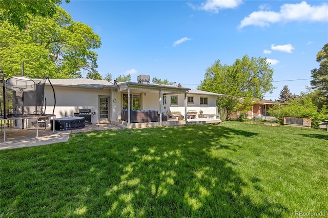 13402 W 24th Pl, Golden, CO 80401 - rear view of house featuring a trampoline, a patio area, a lawn, and a hot tub
