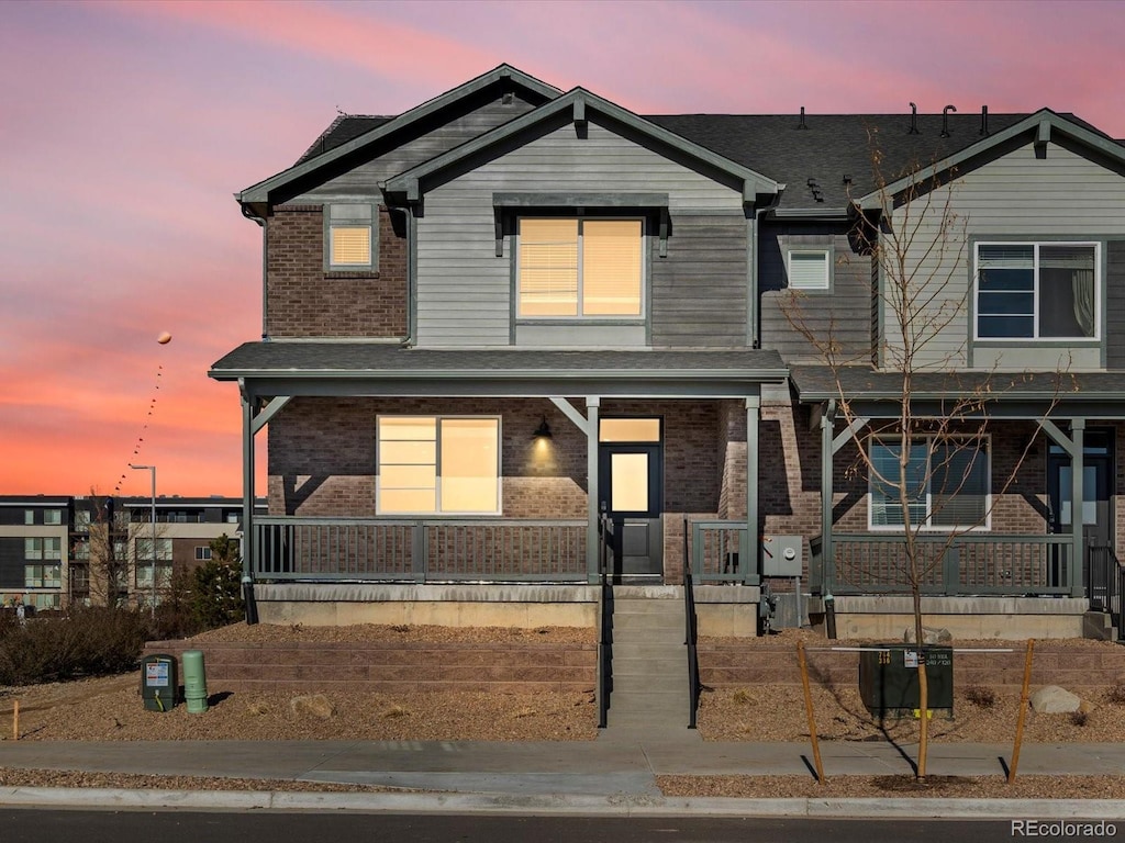 view of front of home featuring covered porch and brick siding