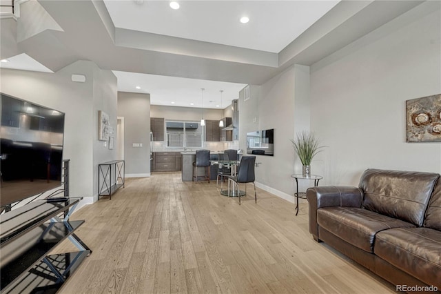 living area with light wood-type flooring, baseboards, and recessed lighting