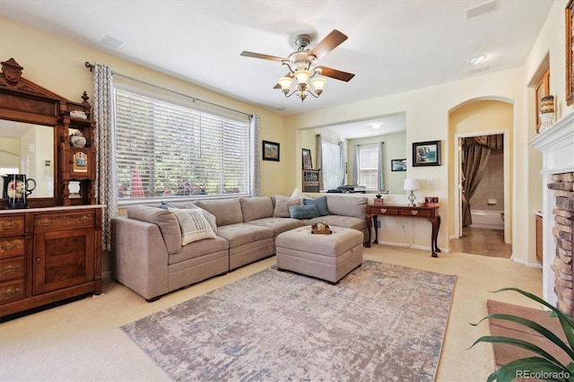 17298 E Lake Pl, Aurora, CO 80016 - living area with light carpet, a stone fireplace, a ceiling fan, and arched walkways