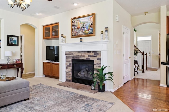 17298 E Lake Pl, Aurora, CO 80016 - living room with arched walkways, a stone fireplace, and light carpet