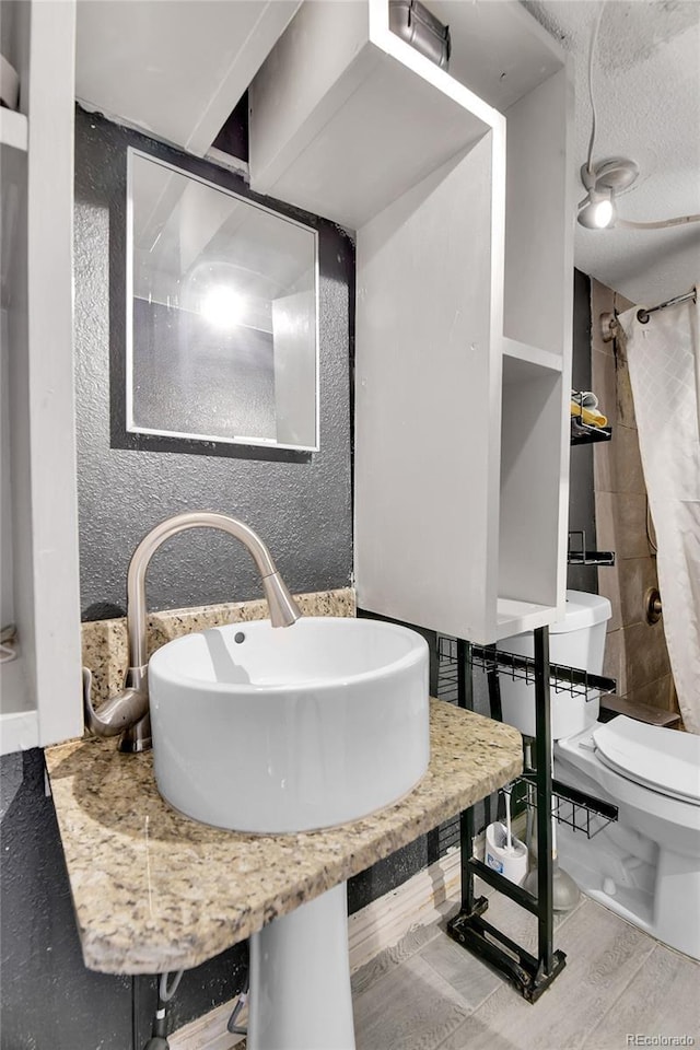 8430 Madison Way, Denver, CO 80229 - bathroom featuring toilet, a shower with curtain, a sink, and a textured wall