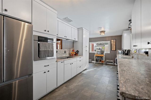 kitchen featuring sink, stainless steel appliances, white cabinetry, and decorative backsplash