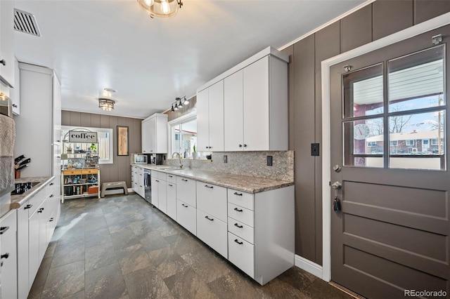 kitchen featuring dishwasher, sink, white cabinets, light stone counters, and black electric cooktop