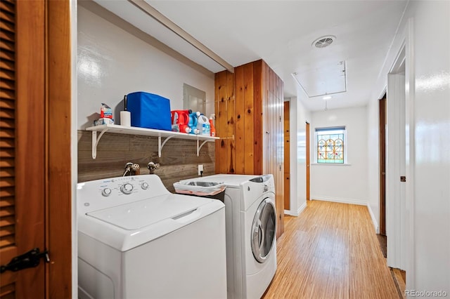 laundry area with light hardwood / wood-style flooring and washing machine and clothes dryer