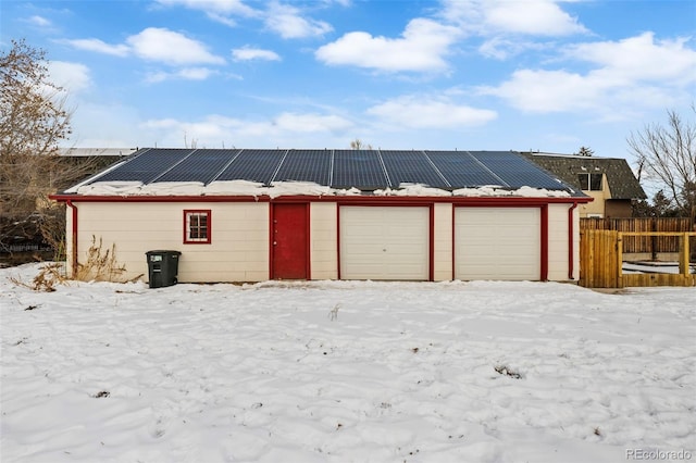 snow covered garage with solar panels