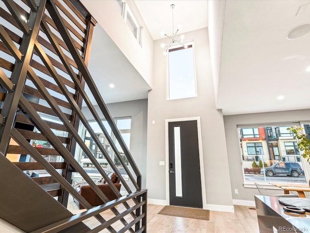 entrance foyer with a high ceiling, a chandelier, and light hardwood / wood-style floors