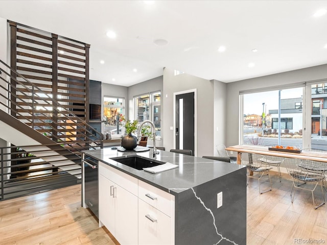 kitchen featuring white cabinetry, sink, a wealth of natural light, and a kitchen island with sink