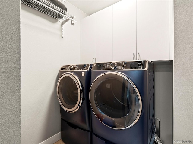 clothes washing area featuring cabinets and independent washer and dryer