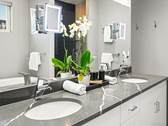 full bath with double vanity, a sink, and a bathtub