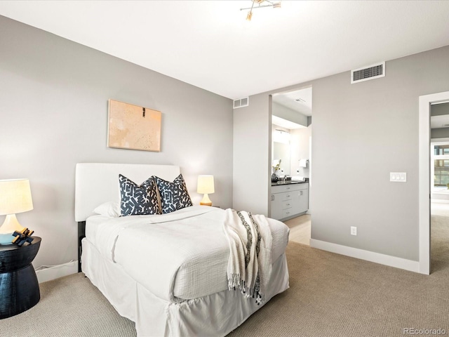 bedroom with ensuite bath, carpet flooring, visible vents, and baseboards