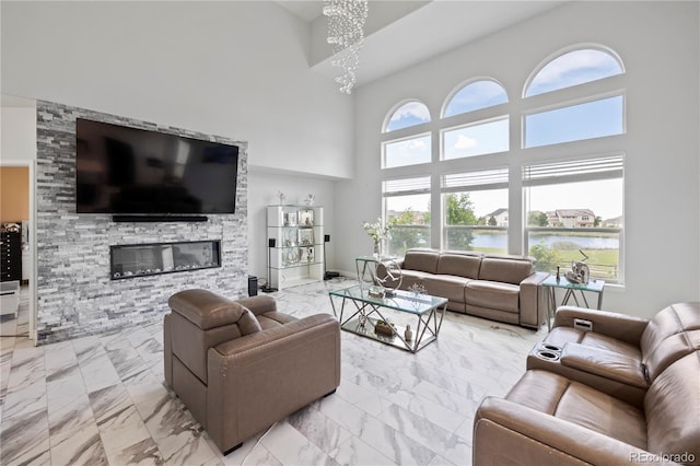 12404 Pine Valley Cir, Peyton, CO 80831 - living room featuring light marble finish floors, a towering ceiling, a water view, a chandelier, and a stone fireplace