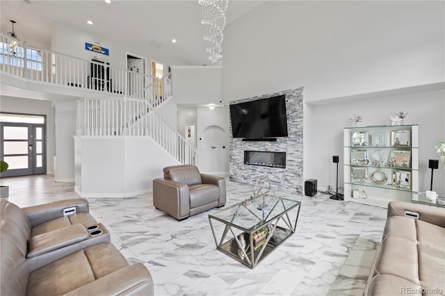 12404 Pine Valley Cir, Peyton, CO 80831 - living room featuring a towering ceiling, a chandelier, stairway, a stone fireplace, and marble finish floors