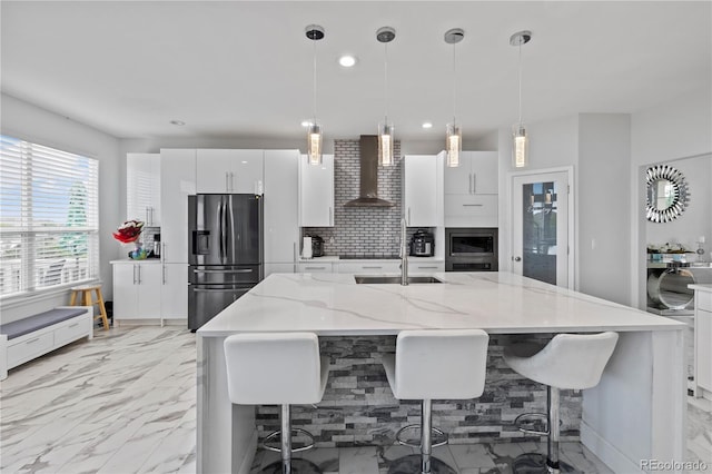 12404 Pine Valley Cir, Peyton, CO 80831 - kitchen featuring stainless steel fridge with ice dispenser, wall chimney exhaust hood, decorative backsplash, white cabinetry, and a kitchen bar