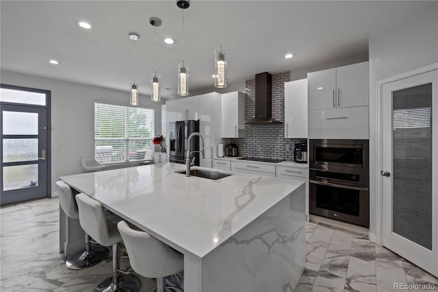 12404 Pine Valley Cir, Peyton, CO 80831 - kitchen with wall chimney range hood, stainless steel appliances, light marble finish flooring, white cabinetry, and recessed lighting