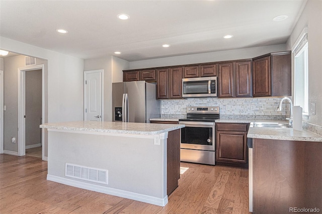 kitchen featuring a kitchen island, sink, light hardwood / wood-style floors, and stainless steel appliances