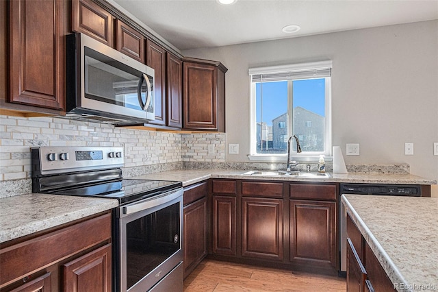 kitchen with sink, backsplash, dark brown cabinets, appliances with stainless steel finishes, and light wood-type flooring