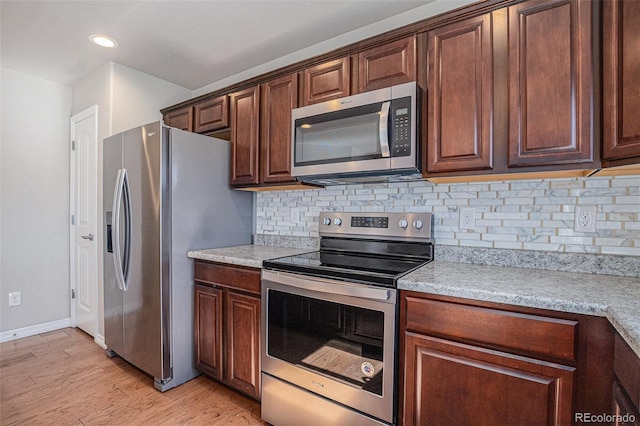 kitchen featuring appliances with stainless steel finishes, tasteful backsplash, light hardwood / wood-style flooring, and light stone counters