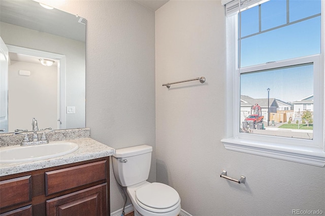 bathroom featuring vanity, toilet, and a healthy amount of sunlight