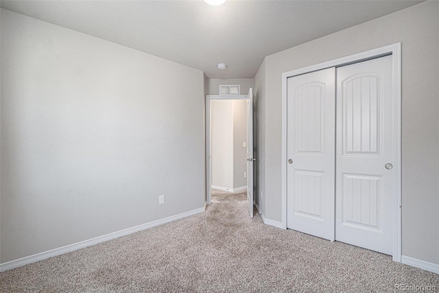 unfurnished bedroom featuring light carpet and a closet